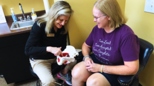 Photo showing one-on-one patient care the Cantrell Center in Warner Robins, GA near Macon, GA. Physical therapist points to a model of a pelvis during a patient evaluation.